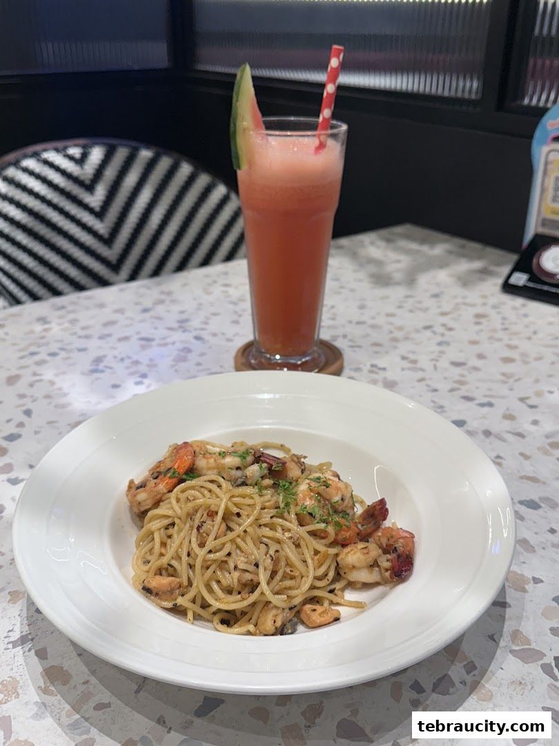 A plate of seafood pasta and a refreshing watermelon juice with a slice of watermelon.