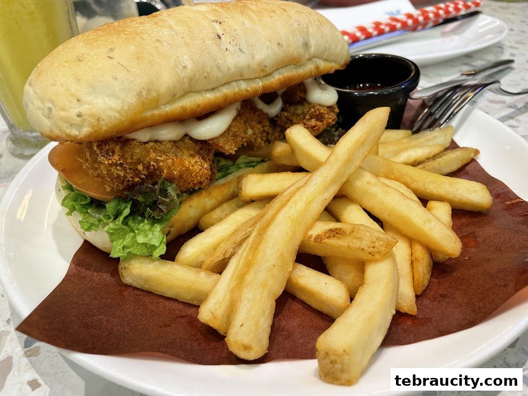 A close-up shot of a delicious sandwich with fries and a side of sauce.