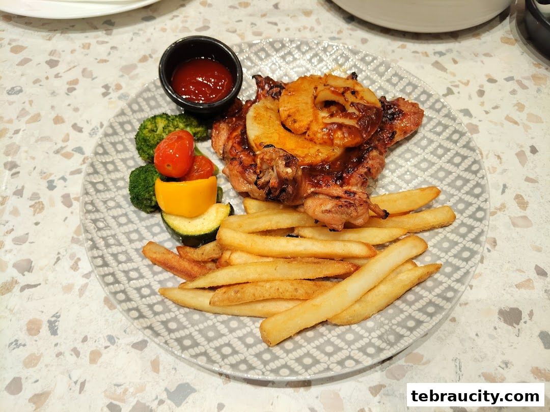A delicious grilled chicken dish with pineapple, fries, and mixed vegetables served on a patterned plate.