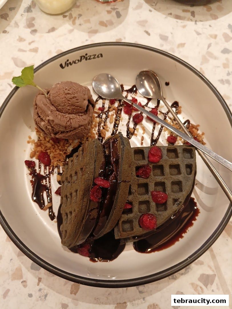 A delicious chocolate waffle with ice cream and berries, served on a plate.