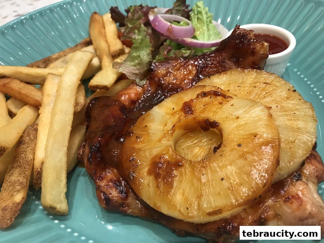 A close-up shot of a delicious grilled chicken dish with pineapple slices and french fries.