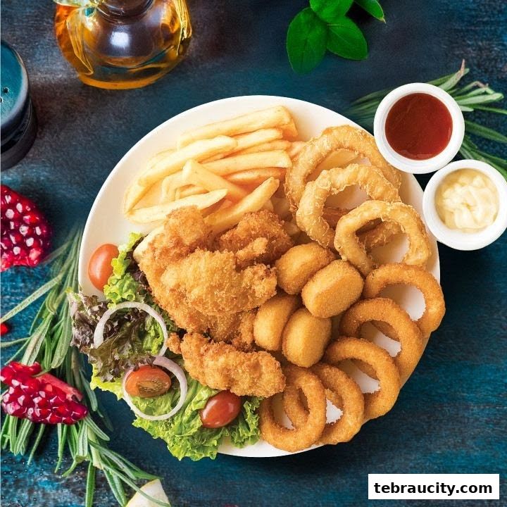 A platter of fried chicken, french fries, onion rings, and nuggets with dipping sauces.