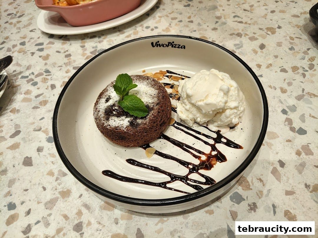 A chocolate lava cake with ice cream and mint garnish on a plate.
