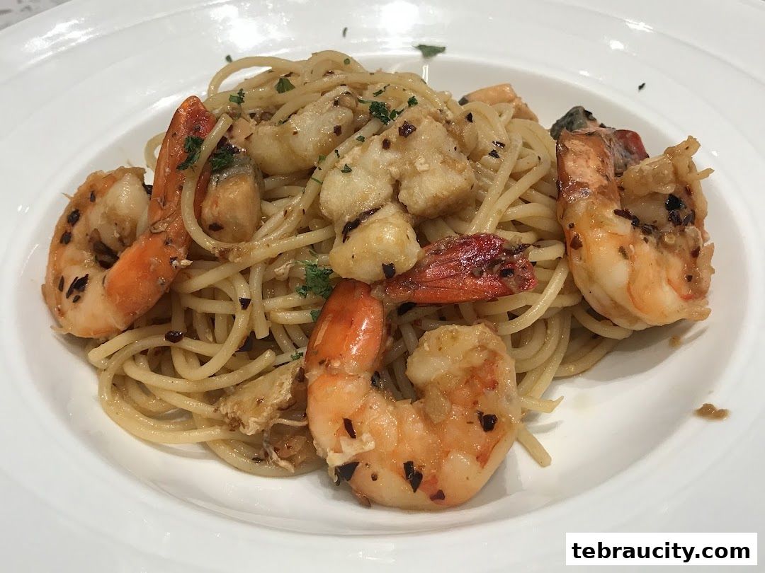 A plate of spaghetti with prawns and garlic, garnished with parsley.