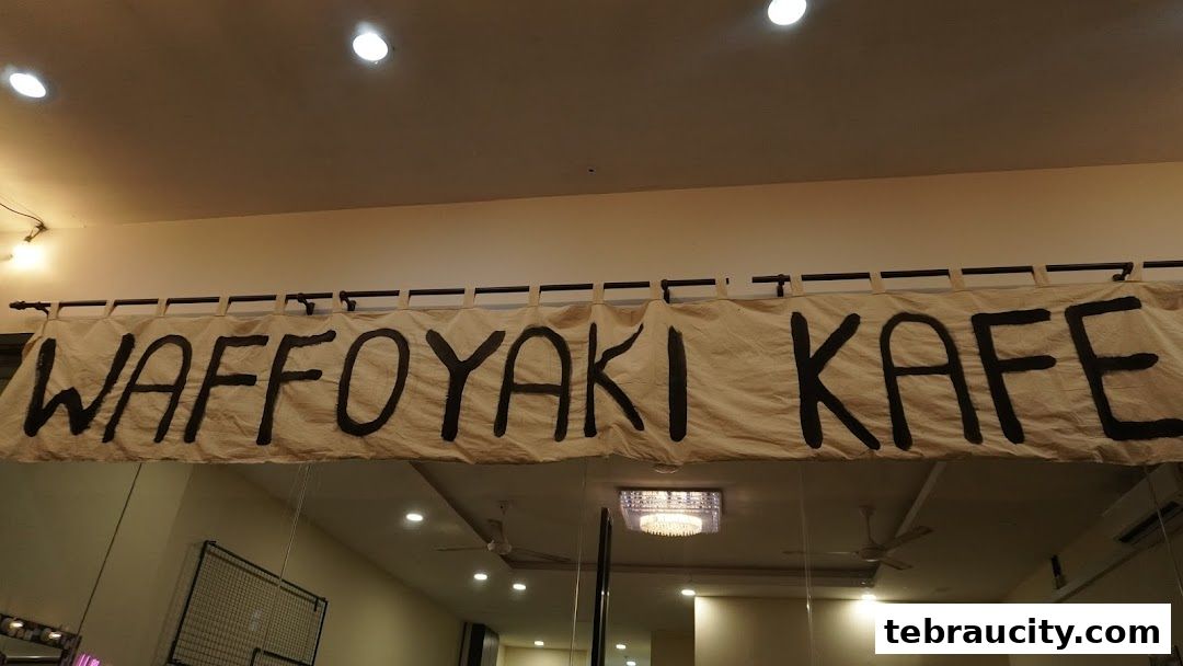 A banner with the text "WAFFOYAKI KAFE" hangs above a reflective surface.