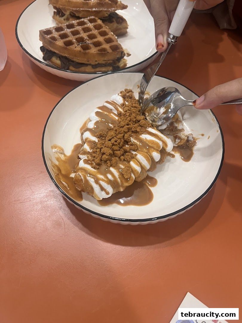 A close-up of two delicious waffles, one topped with cream and caramel sauce.
