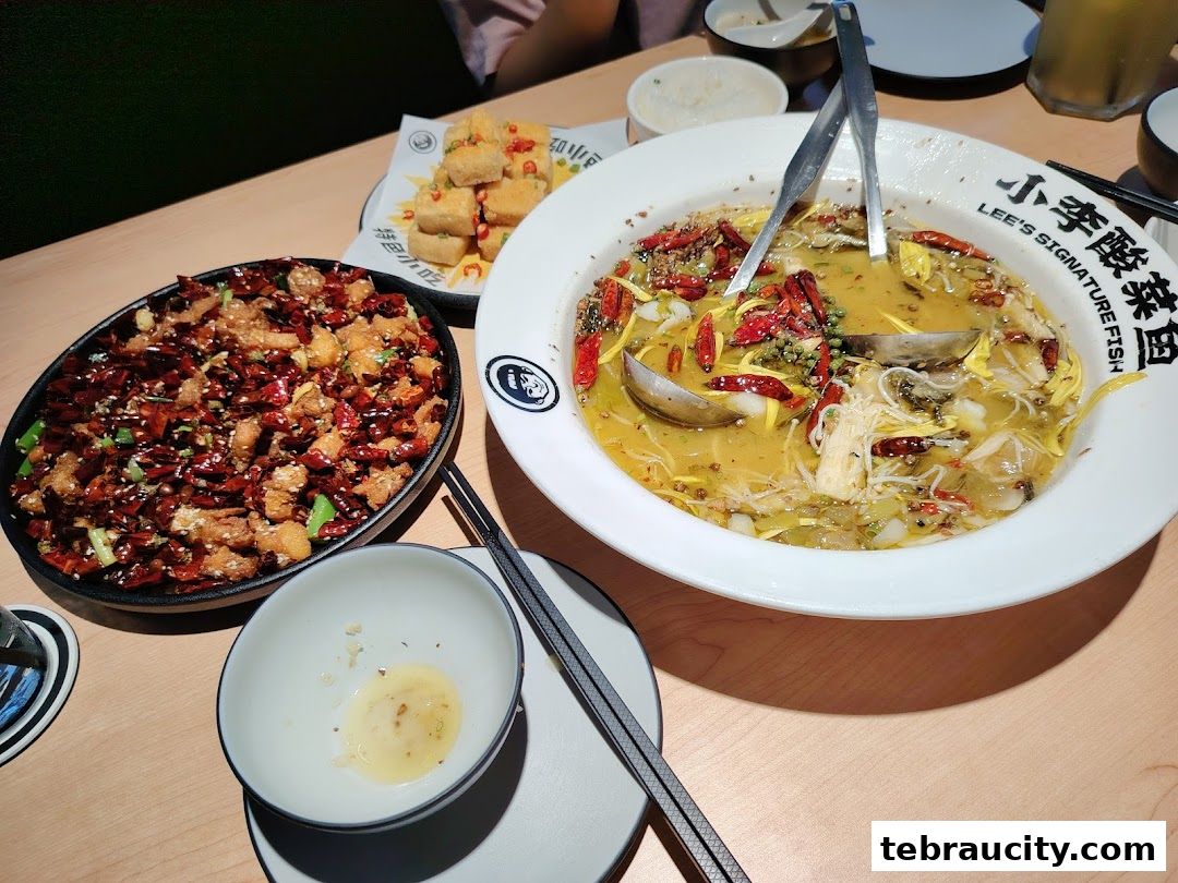 A table laden with delicious Chinese dishes, including a large bowl of fish soup and crispy fried chicken.