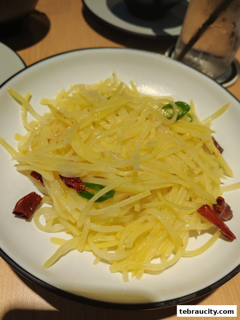 A close-up shot of a delicious stir-fried shredded potato dish with chili peppers.