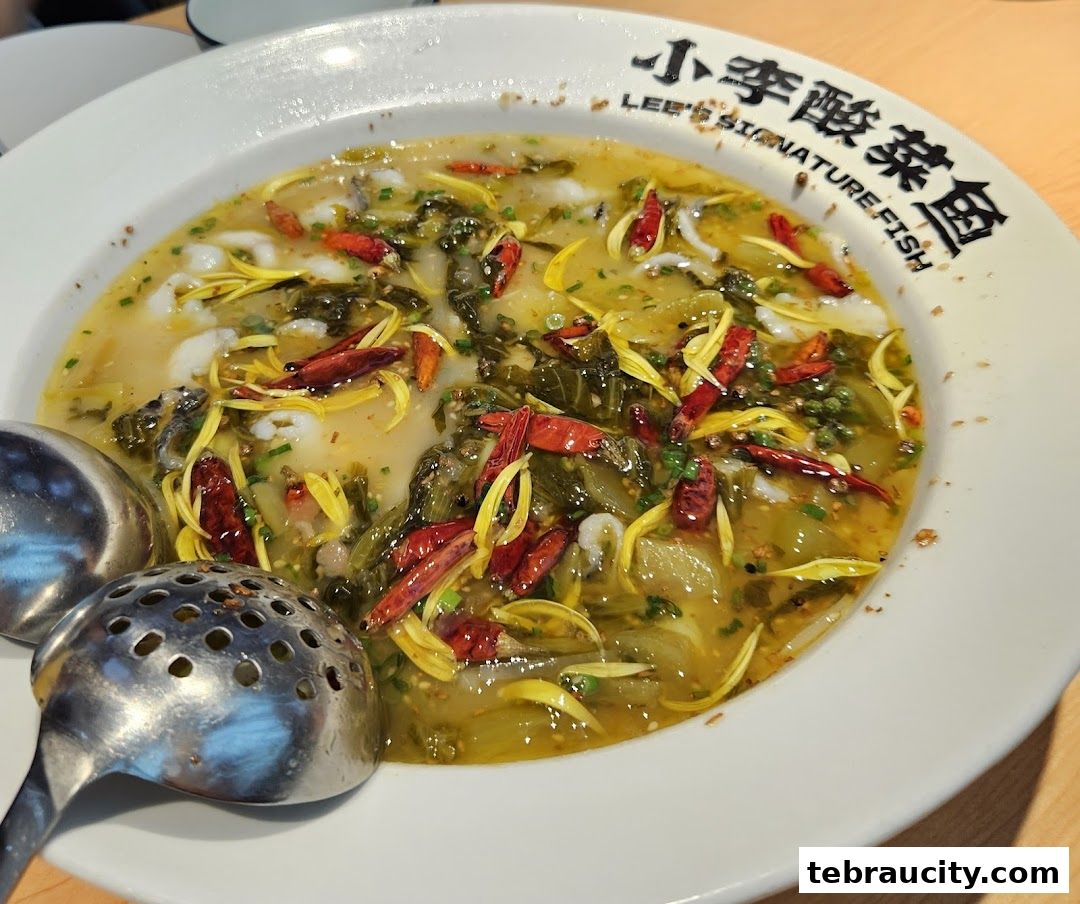 A close-up of a steaming bowl of pickled vegetable fish with chili peppers and herbs.