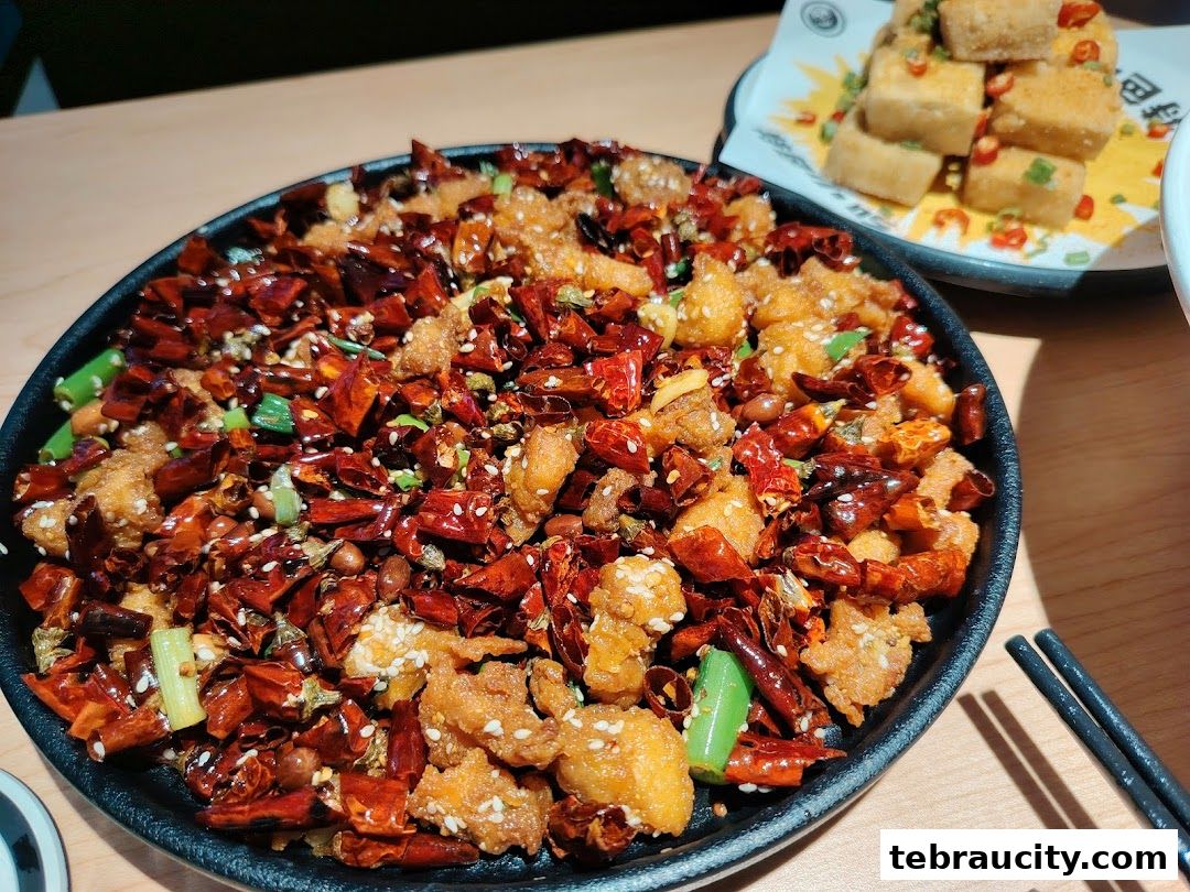 A close-up of a spicy Sichuan dish with fried chicken, chili peppers, and peanuts.