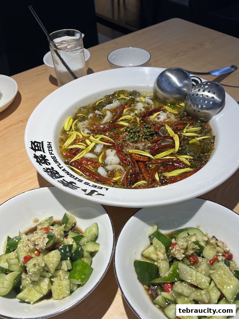 A close-up of a flavorful Sichuan pickled fish dish with side dishes of cucumber salad.