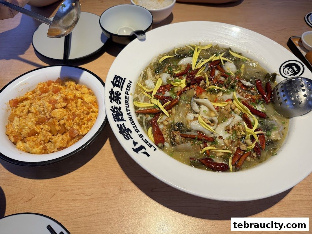 A close-up of a delicious Sichuan-style pickled fish dish with a side of scrambled eggs with tomatoes.