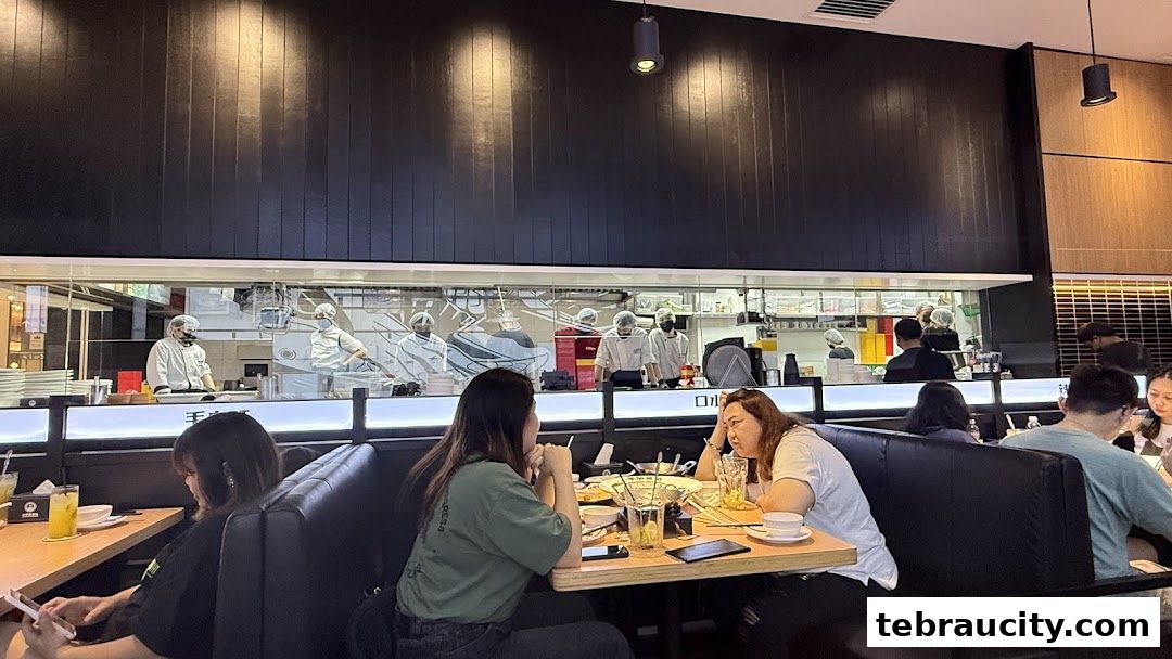 Diners seated at tables in a restaurant with an open kitchen view.