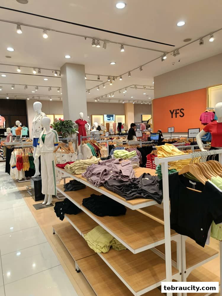 Interior view of a clothing store with mannequins and neatly folded apparel on display shelves.