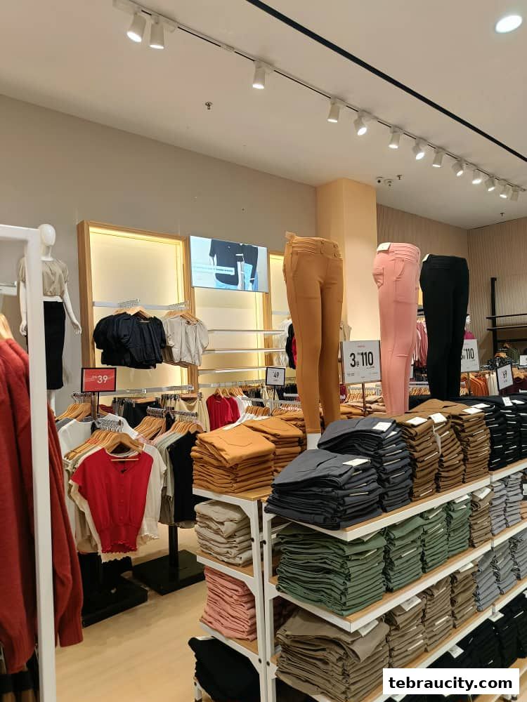 Interior of a clothing store with mannequins and neatly folded pants on display.