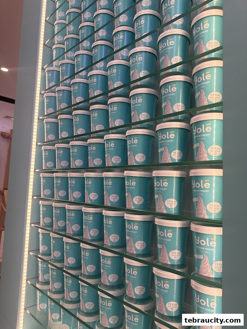 A wall display filled with tubs of Yolé frozen yogurt in various sizes.