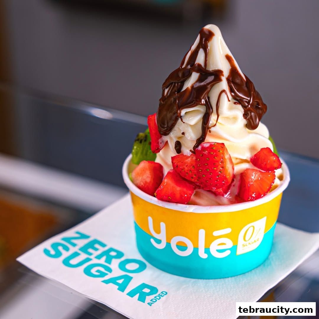 A cup of frozen yogurt topped with chocolate sauce and fresh fruit.