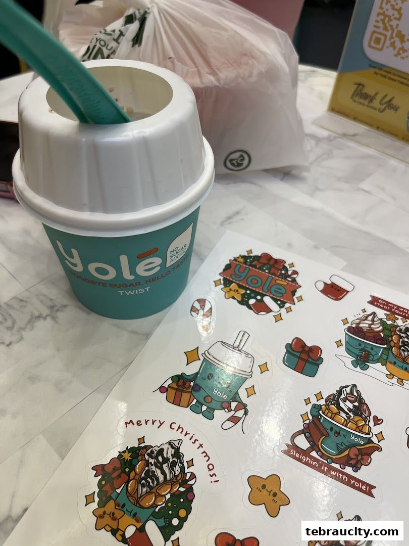 A Yolé frozen yogurt cup with a straw and Christmas-themed stickers.