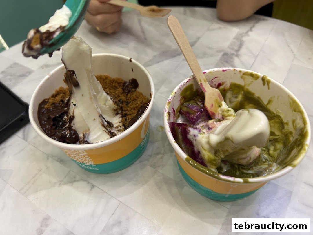 Two cups of frozen yogurt with toppings, one with chocolate and cookie crumble, the other with matcha and purple sweet potato.