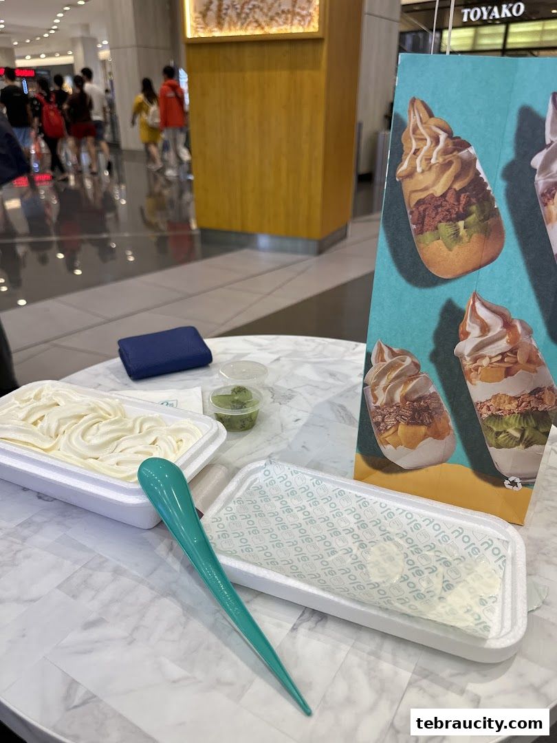 A table with Yolé frozen yogurt and toppings, with a promotional poster in the background.