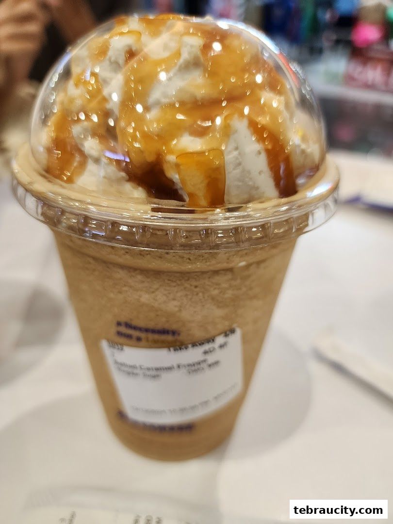 A close-up of a caramel frappe topped with whipped cream and caramel drizzle.