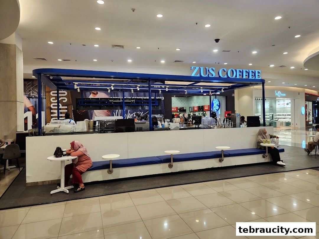 A ZUS Coffee shop with customers seated at tables inside a mall.