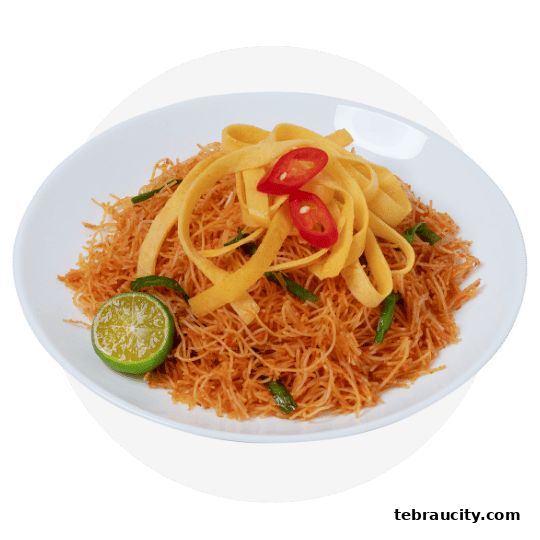 A plate of stir-fried noodles with egg, chili, and lime.