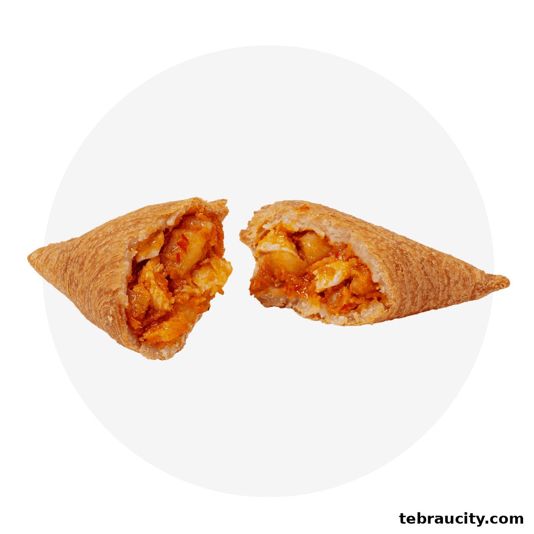 A savory pastry, split in half, revealing a filling of chicken and sauce.