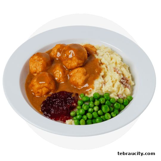 A plate of meatballs with mashed potatoes, peas, and cranberry sauce.