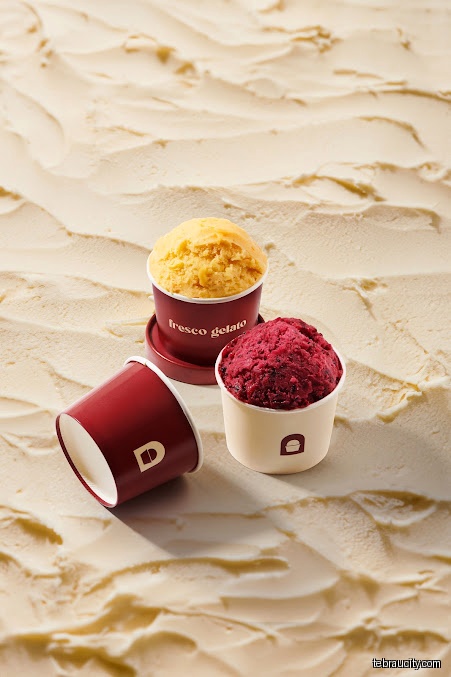 Three cups of Fresco Gelato in different flavors on a textured surface.